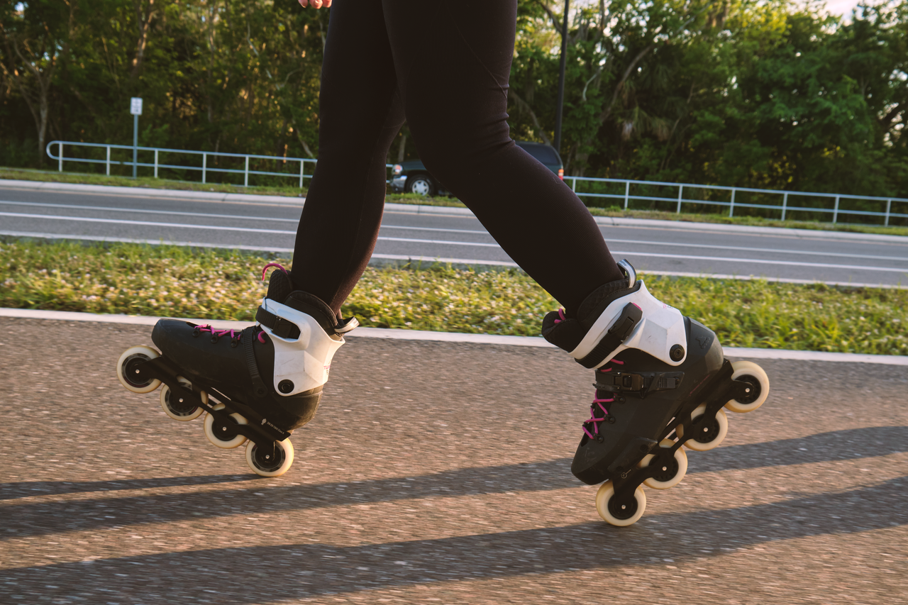 Close-up of rollerblades on a smooth path by the road, enjoying the sun.